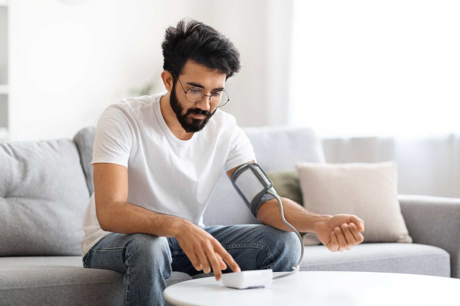 Concentrated Indian Man Monitoring His Blood Pressure With Digital Sphygmomanometer Scaled